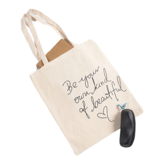 Off-white canvas tote bag with text 'Be your own kind of beautiful' printed on the front, along with a keychain.