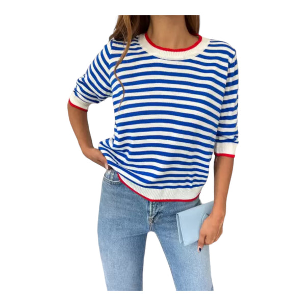 A woman wearing a white and blue striped knit blouse with a round crew-neck and 3/4 sleeves, paired with blue jeans.