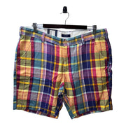 A pair of men's multicolor plaid cargo-style shorts with belt loops and a zipper & button closure, displayed on a hanger.