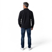 Back view of a man wearing a black COS long-sleeve cotton button-down shirt with a structured collar.