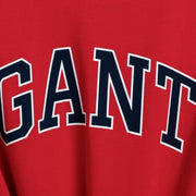 Close-up of GANT red graphic logo T-shirt showing bold navy GANT print detail on cotton fabric