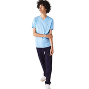 Walking pose of male model wearing Lacoste light blue V-neck T-Shirt with navy pants