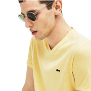 Close-up of Lacoste yellow V-neck T-shirt showing green crocodile logo on chest
