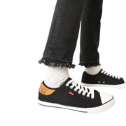 Levi's black canvas sneakers with tan heel patch – worn on feet with frayed hem black jeans, side view