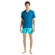 Front view of Vilebrequin blue polo shirt on model paired with bright blue swim shorts